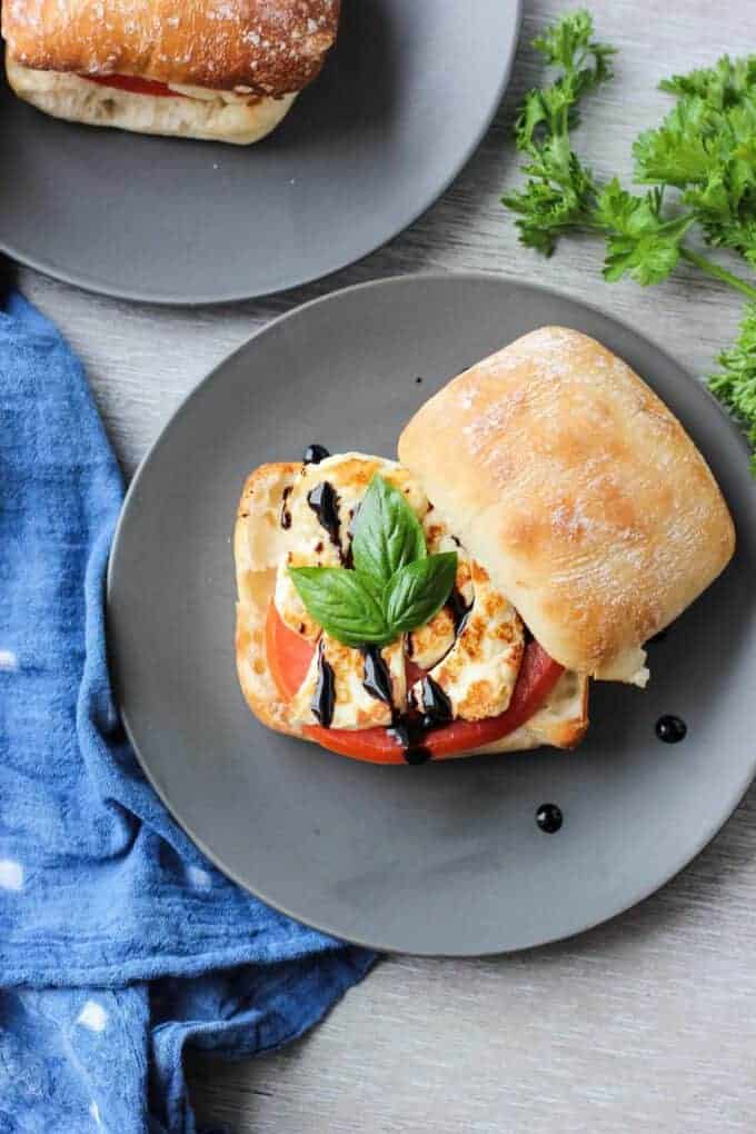 A photo of a halloumi sandwich with fresh basil and balsamic glaze.
