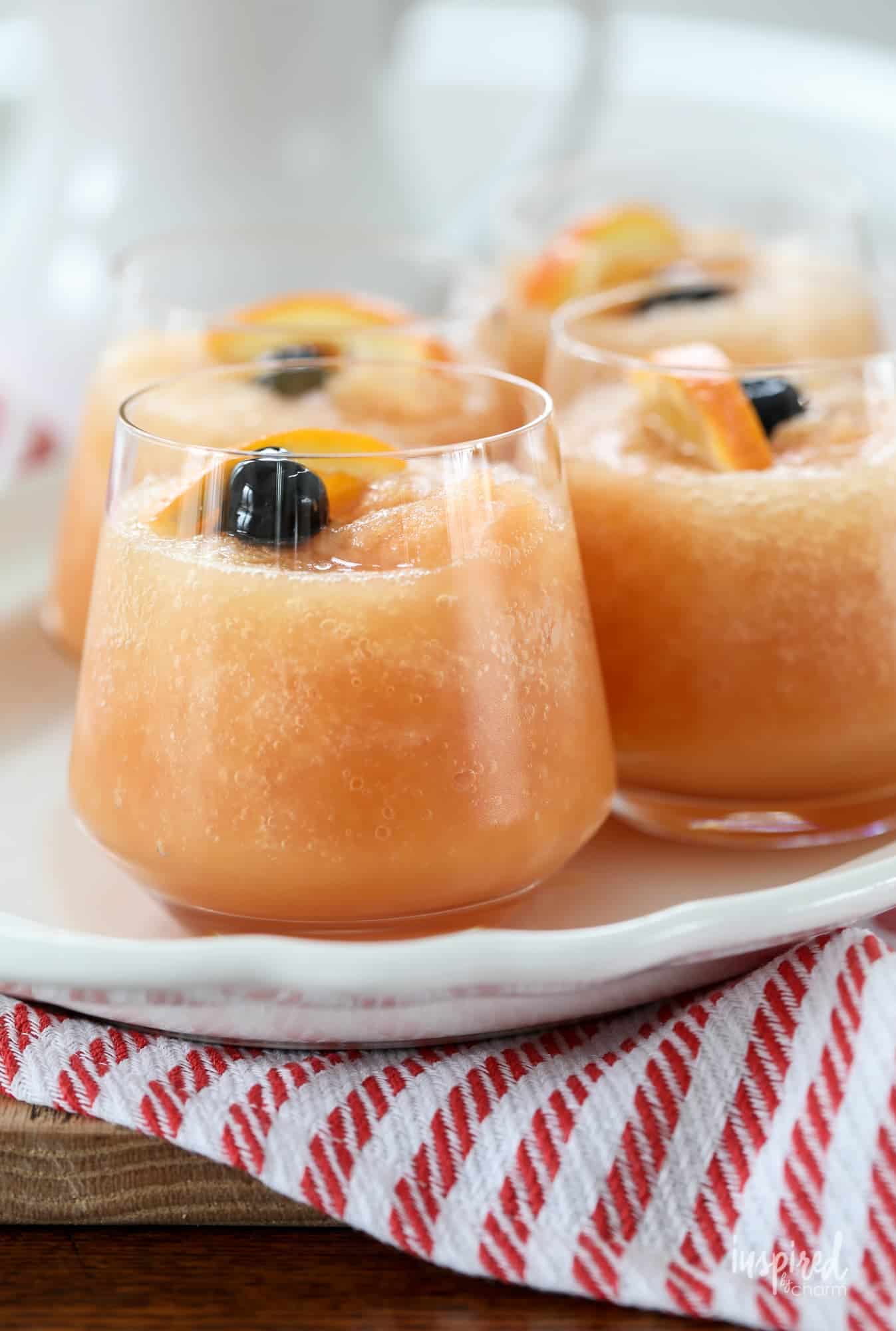 A photo of frozen slushy old fashioneds with cherry and orange garnish.