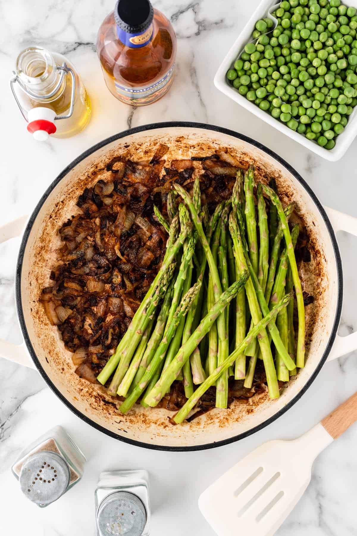 An overhead photo of asparagus and caramelized onions in a pot.