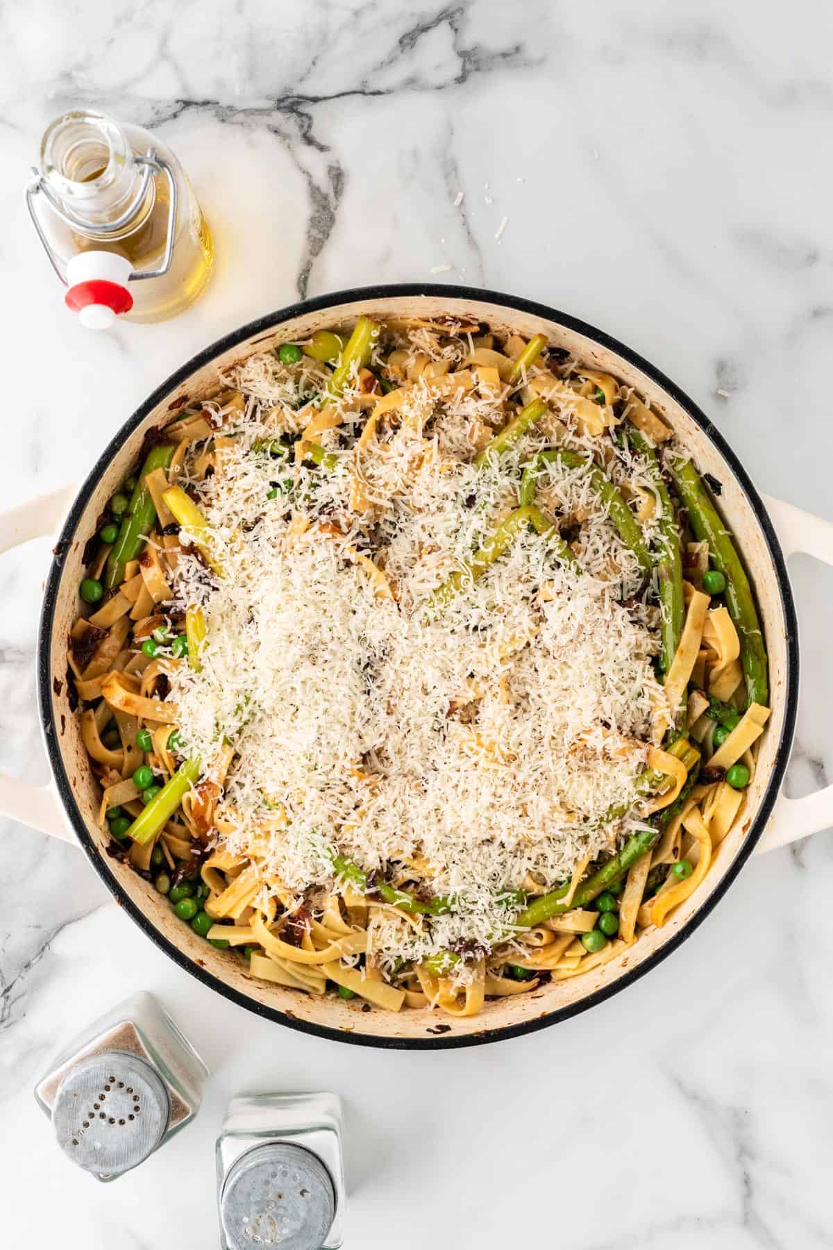 An overhead photo of asparagus pasta in a pot topped with parmesan cheese.