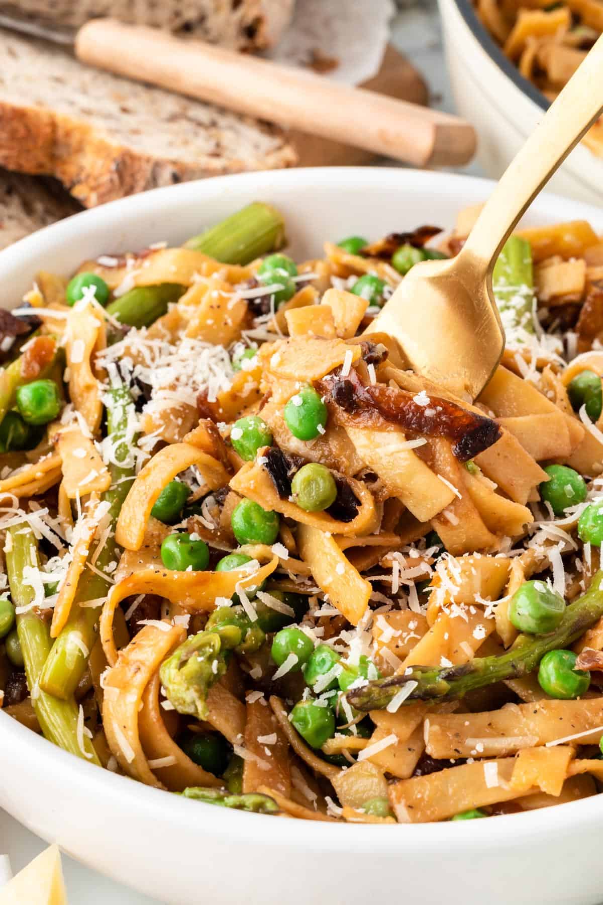 A photo of a fork scooping up some pasta with peas.