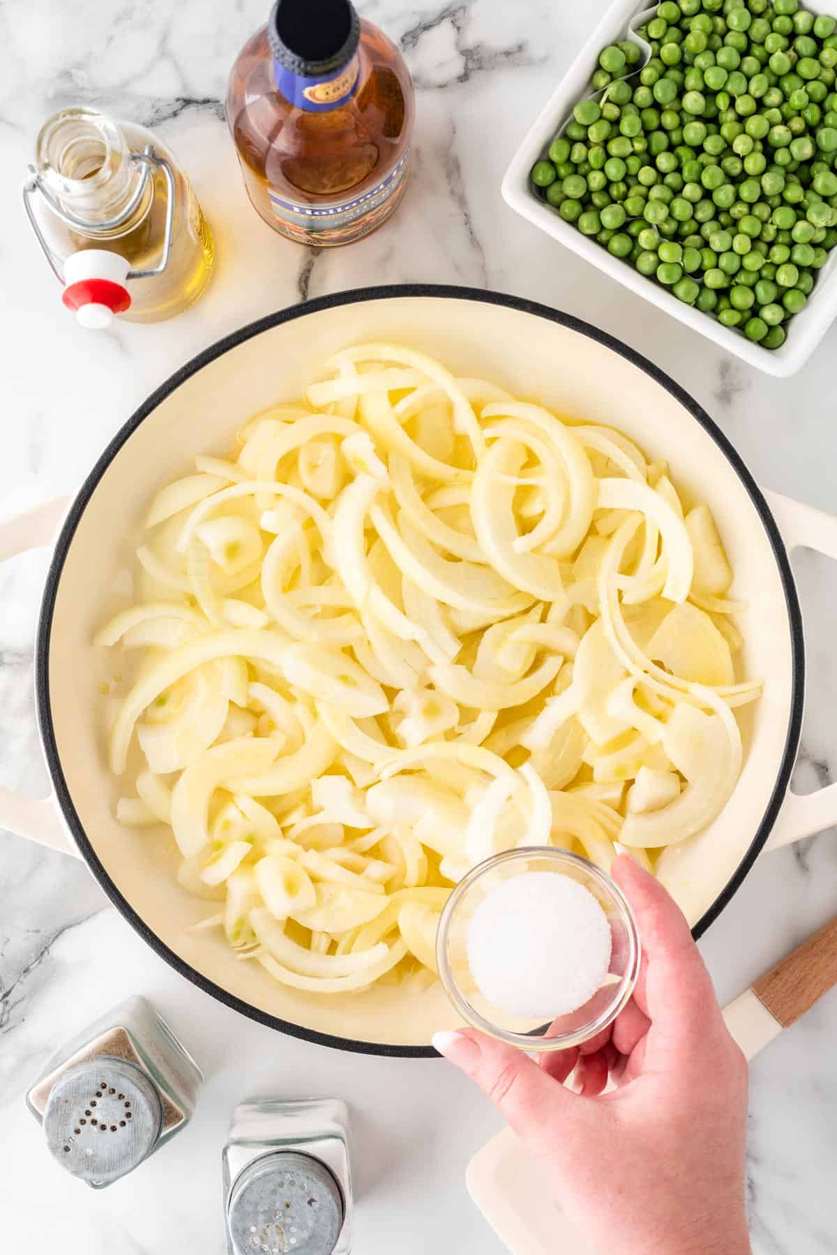 A photo of adding sugar to onions to caramelize in a pot.
