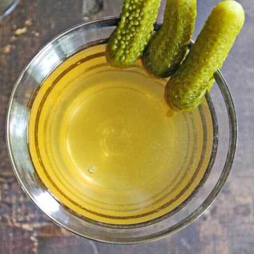A square overhead photo of a dill pickle martini with pickle juice.
