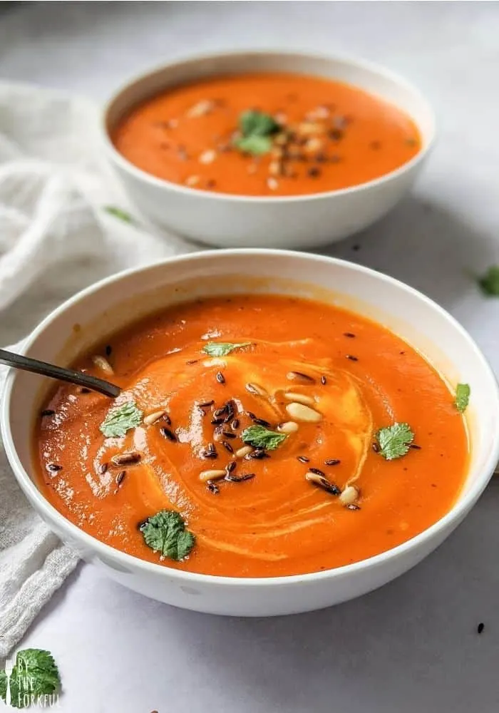 A photo of a bowl of roasted red pepper and butternut squash soup.