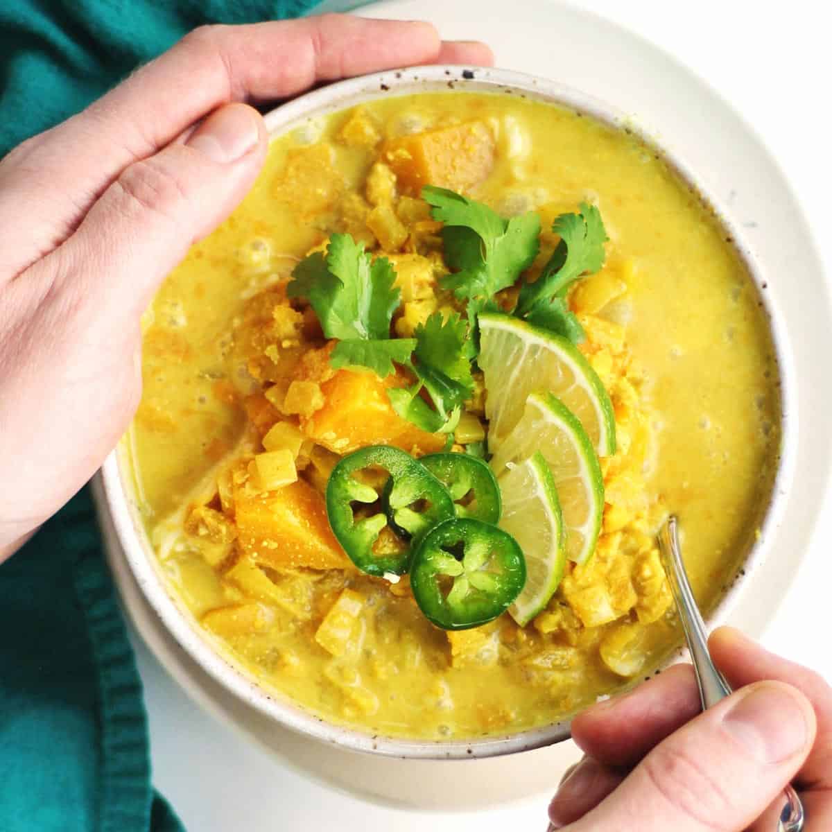 A square photo of curried cauliflower and butternut squash soup in a bowl.