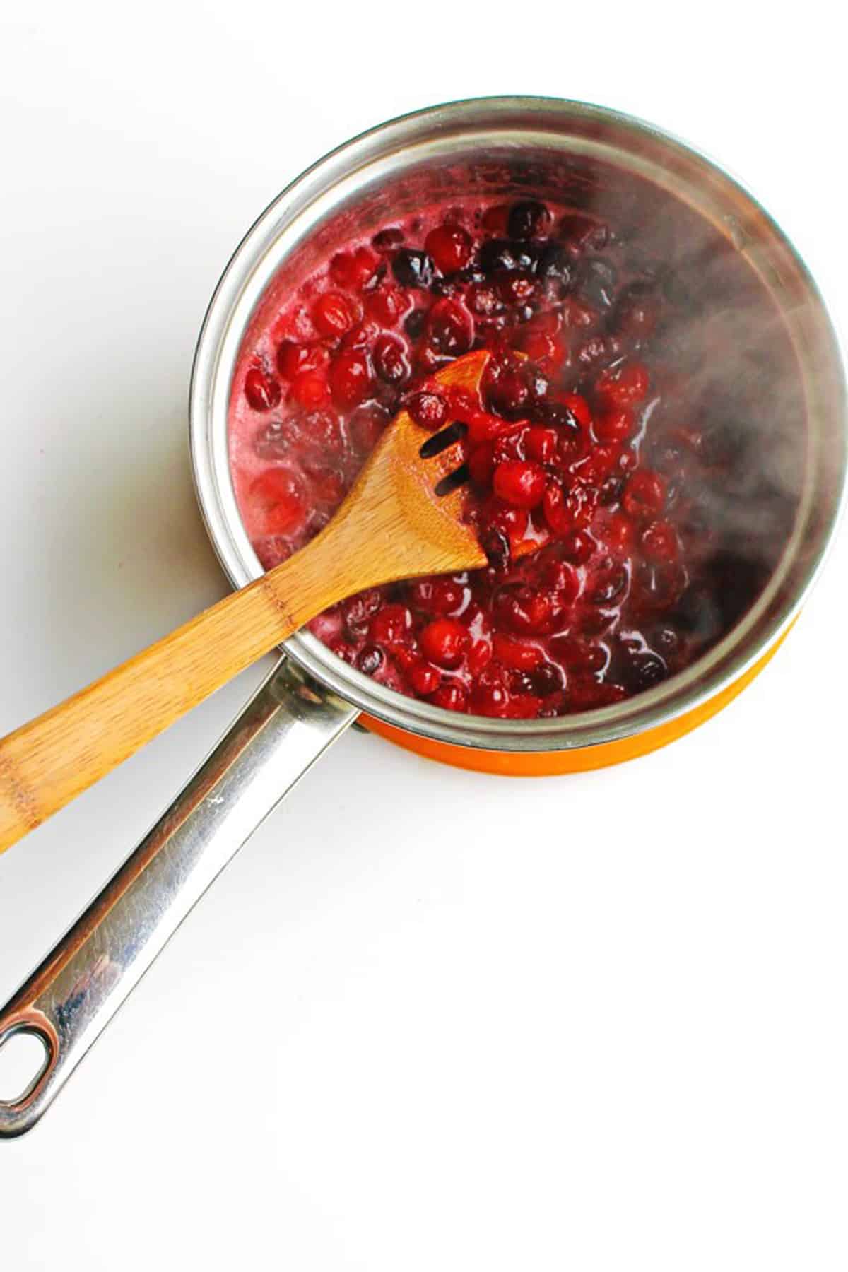 A photo of cranberries cooking in a sauce pan.