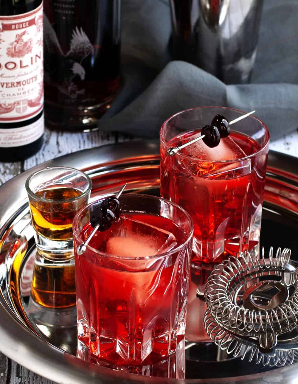 A photo of two boulevardier cocktails on a serving tray.