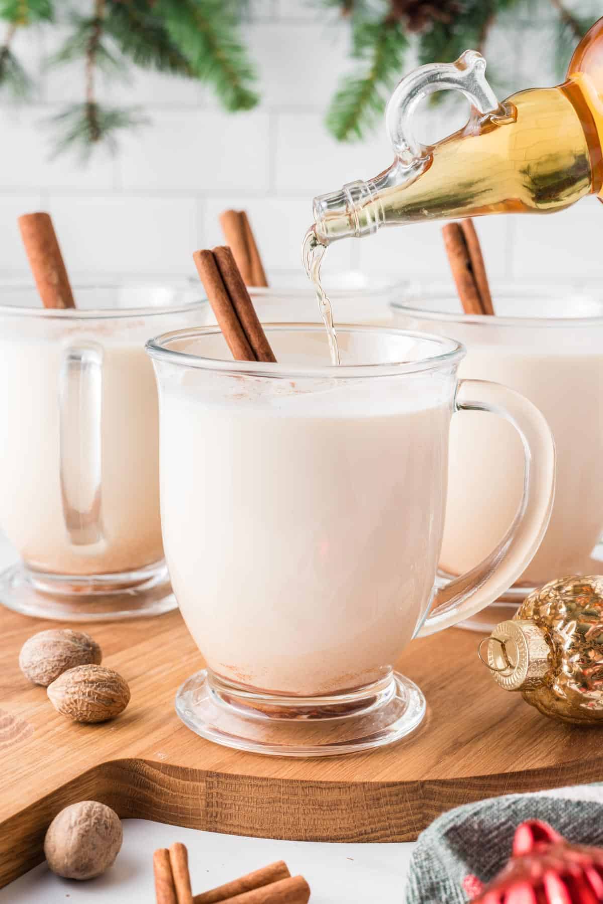 A photo of pouring whiskey into a glass of eggnog.