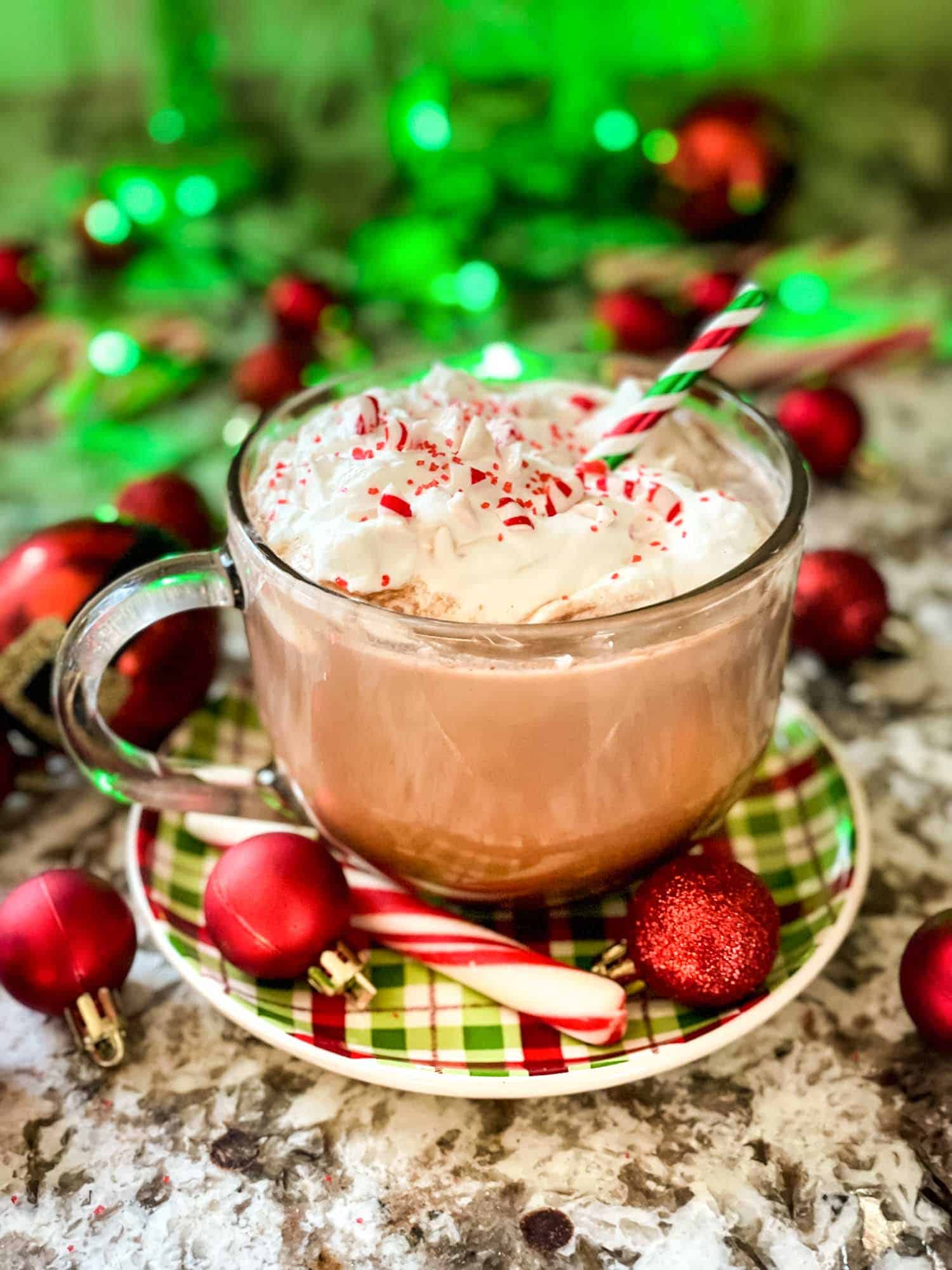 A photo of Christmas hot cocoa with whipped cream with a Christmas themed background.