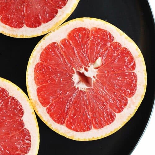 A square photo of a ruby grapefruit cut in half.