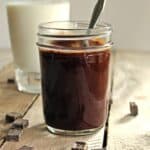 A square photo of peanut butter chocolate sauce in a glass jar.