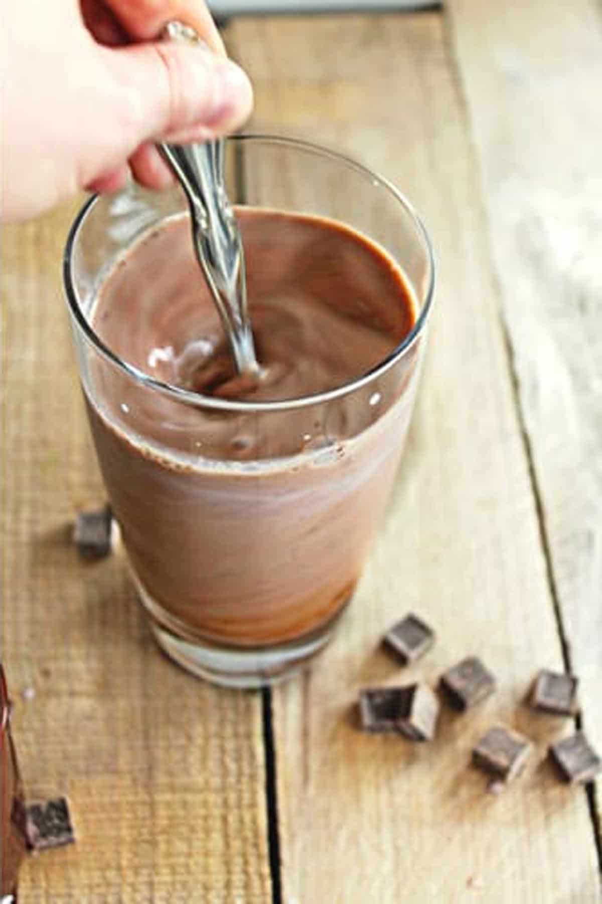 A photo of stirring chocolate syrup into a glass of milk.