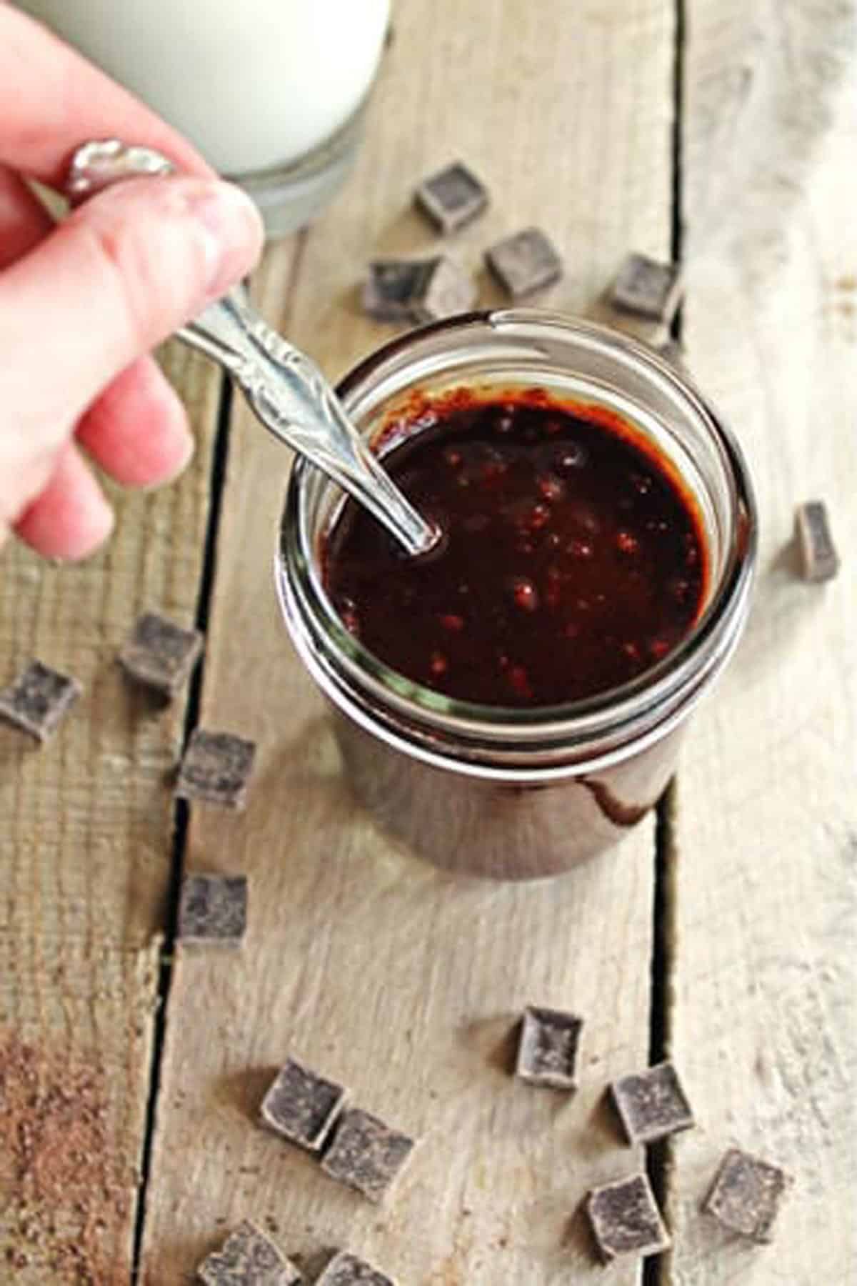 A photo of stirring peanut butter chocolate sauce in a glass jar.